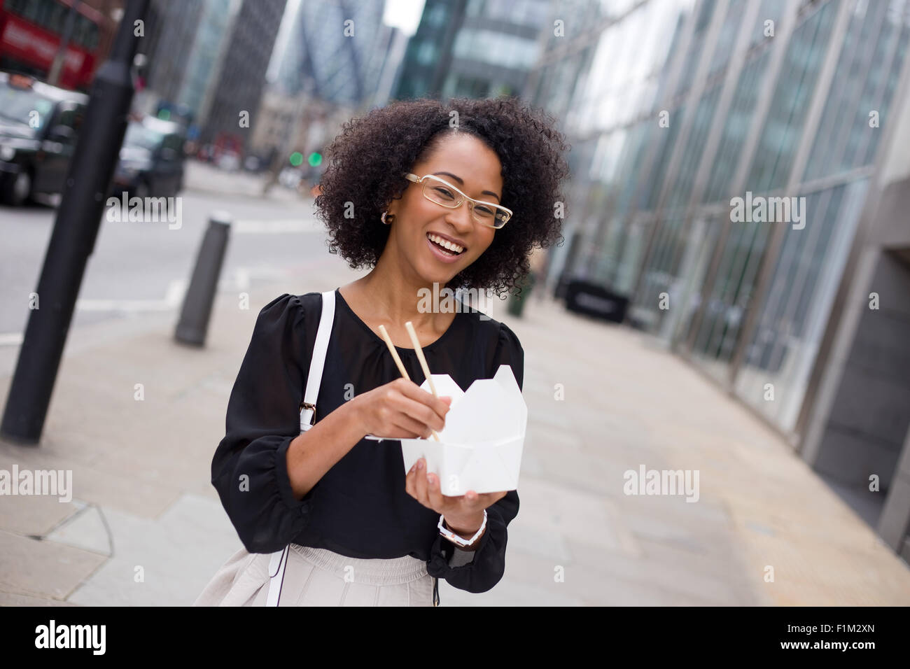 young business woman eating a takeaway in the street Stock Photo