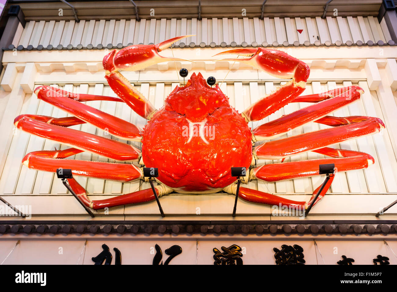 Osaka, Dotonbori. Exterior of famous crab restaurant, Kani Doraku, with giant mechanical orange crab above entrance. Night time, sign illuminated. Stock Photo