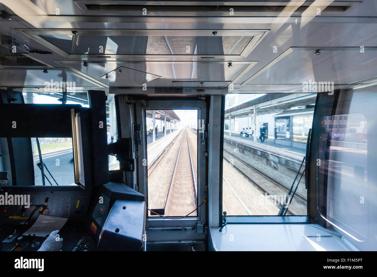 View through the drivers cab  of japanese railway train as it passes through a station at speed. Blurred motion Stock Photo