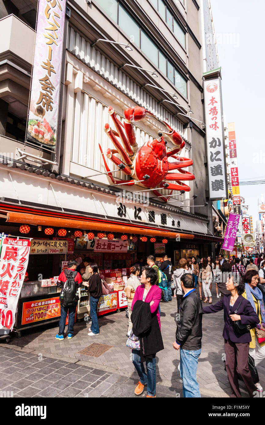 Osaka, Dotonbori. Exterior of famous crab restaurant, Kani Doraku, with giant mechanical orange crab above entrance. Street busy with people walking. Stock Photo