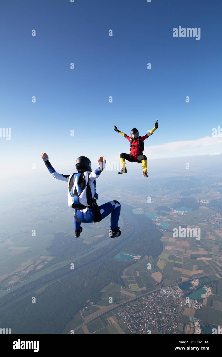 Freefly skydiving team is training formation back/sit-flying over a spectacular lake and fields scenery in the sky with 130 MPH. Stock Photo