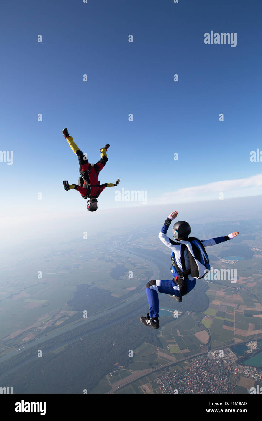Skydiver are flying head up within a team in the sit fly position over a spectacular mountain scenery with over 120 MpH speed. Stock Photo