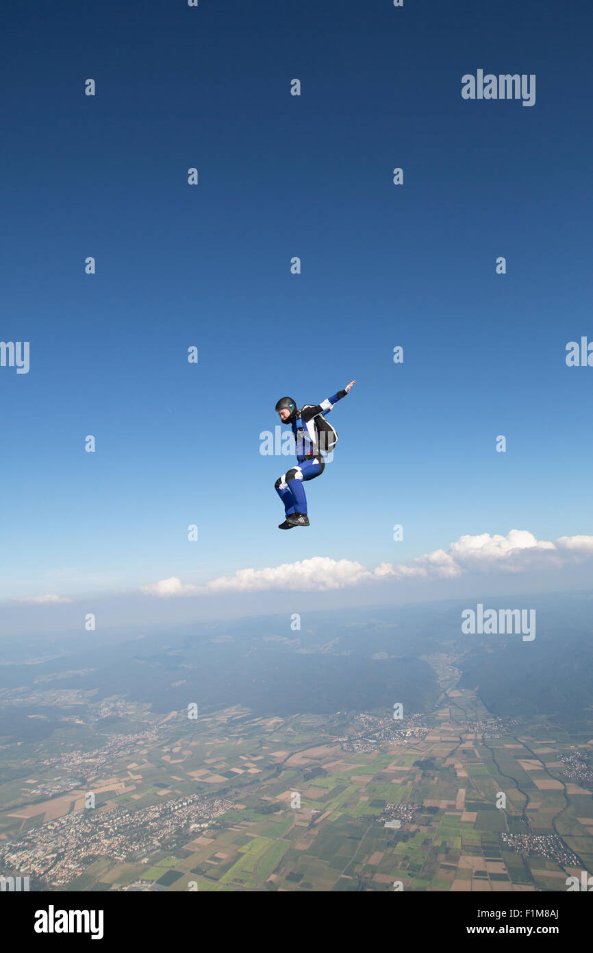 Freefly skydiving man is training in the sit fly position over a spectacular mountain scenery with over 120 MpH speed. Stock Photo