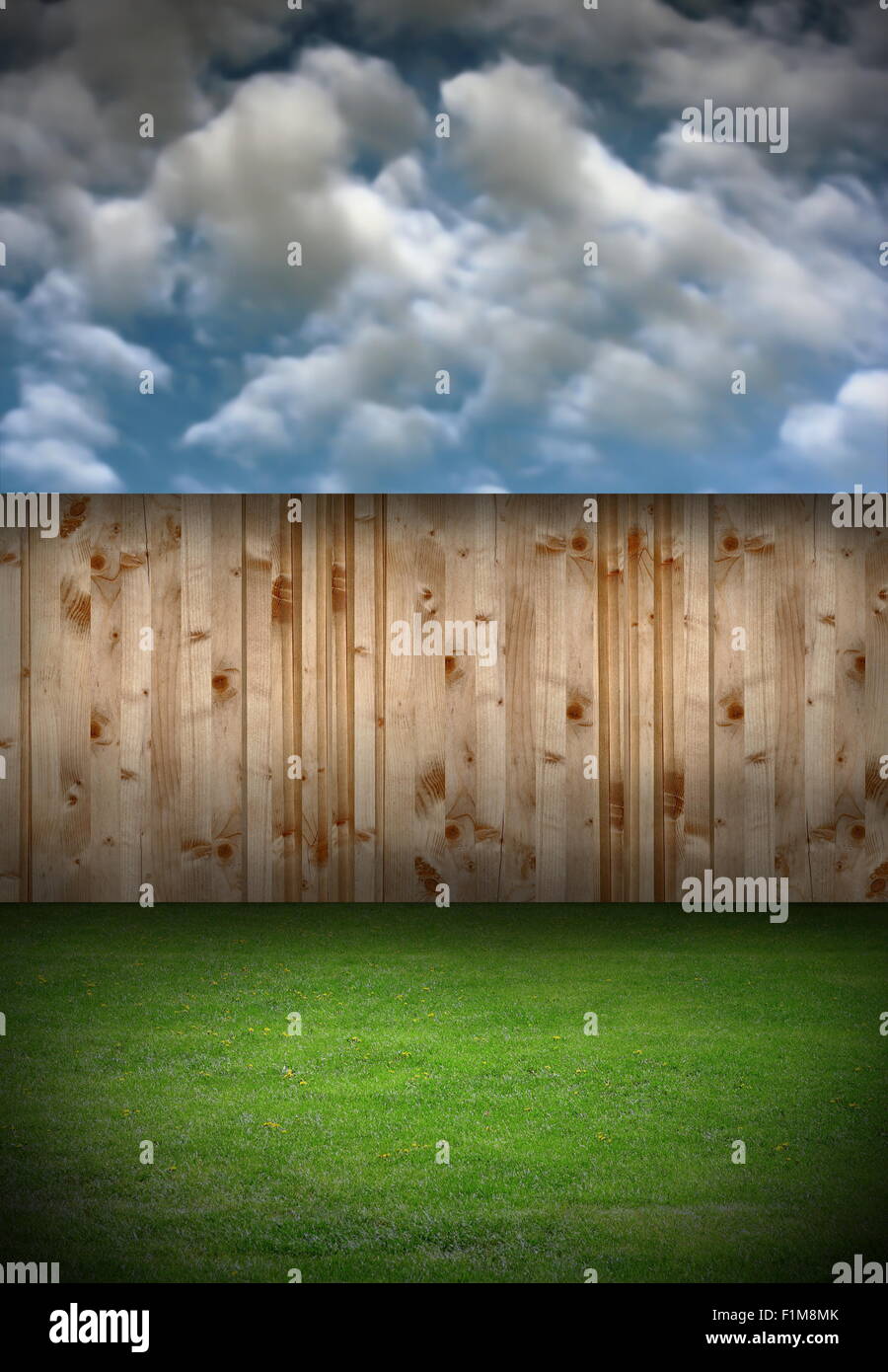 back garden with wooden fence and green fresh turf under cloudy sky Stock Photo