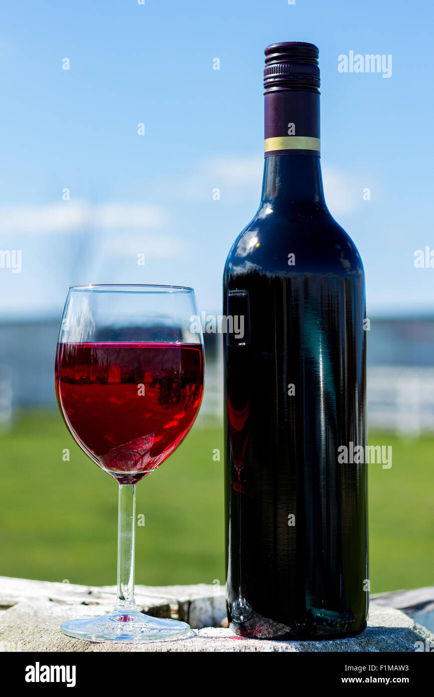 A glasss of red wine and a bottle of wine with a blurred background. Stock Photo