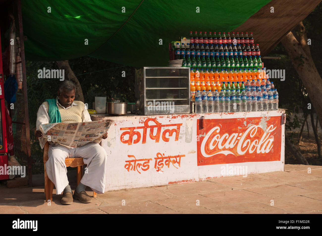Agra, Utar Pradesh, India. Drinks vendor reading newspaper. Stock Photo
