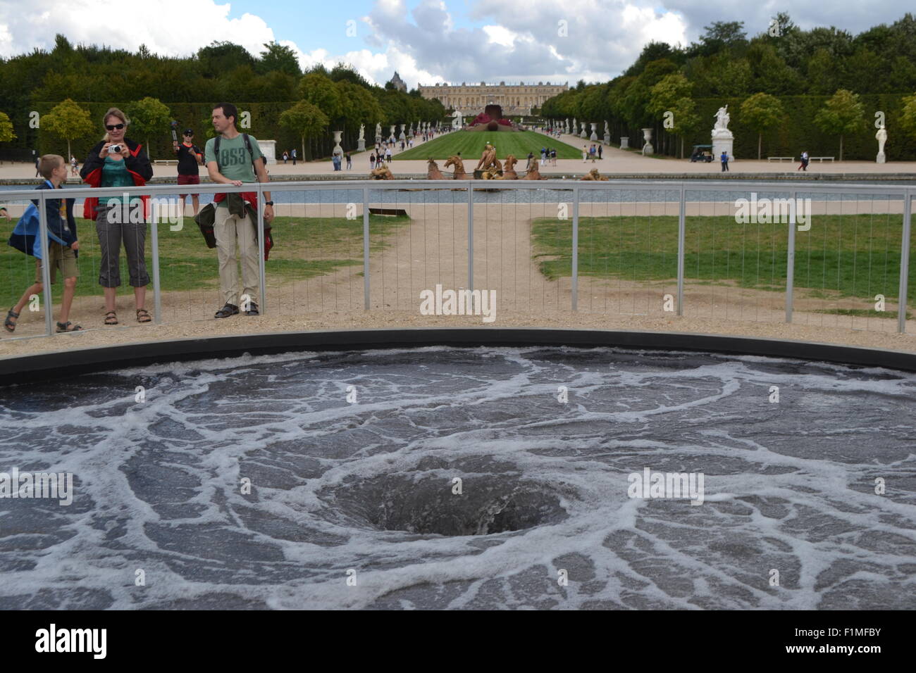 Tourists in the Palace of Versailles look at Decension, a modern art installation by Anish Kapoor. Stock Photo