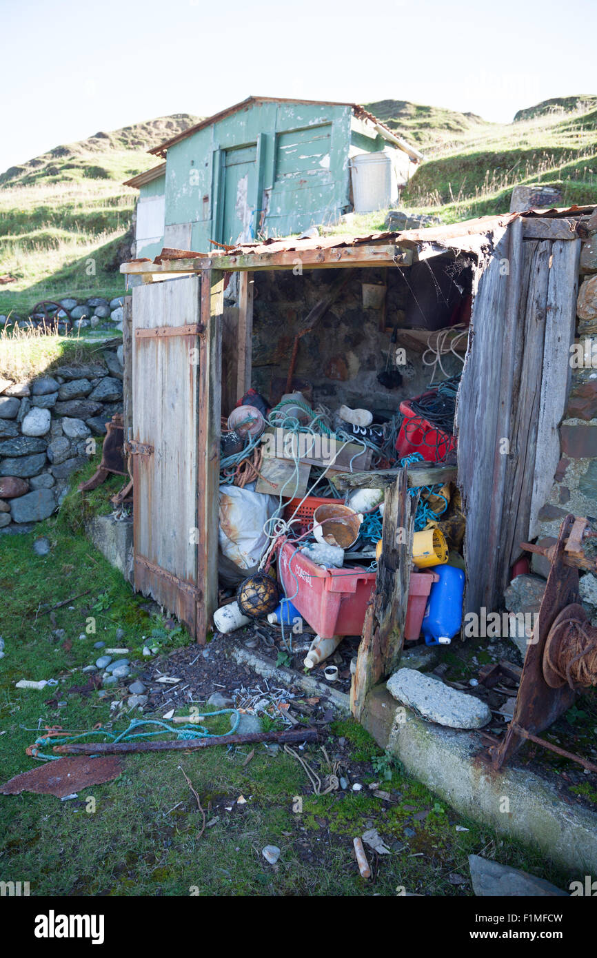 Abandoned fishing huts at Porth Ysgaden, Tudweiliog, Llyn Peninsula, North Wales with rope, boxes, buoys & crates Stock Photo