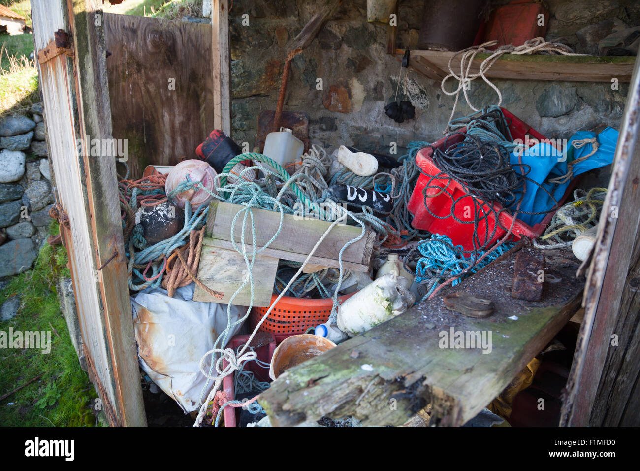 Contents of an abandoned fishing hut at Porth Ysgaden, Tudweiliog, Llyn Peninsula, North Wales with rope, boxes, buoys & crates Stock Photo