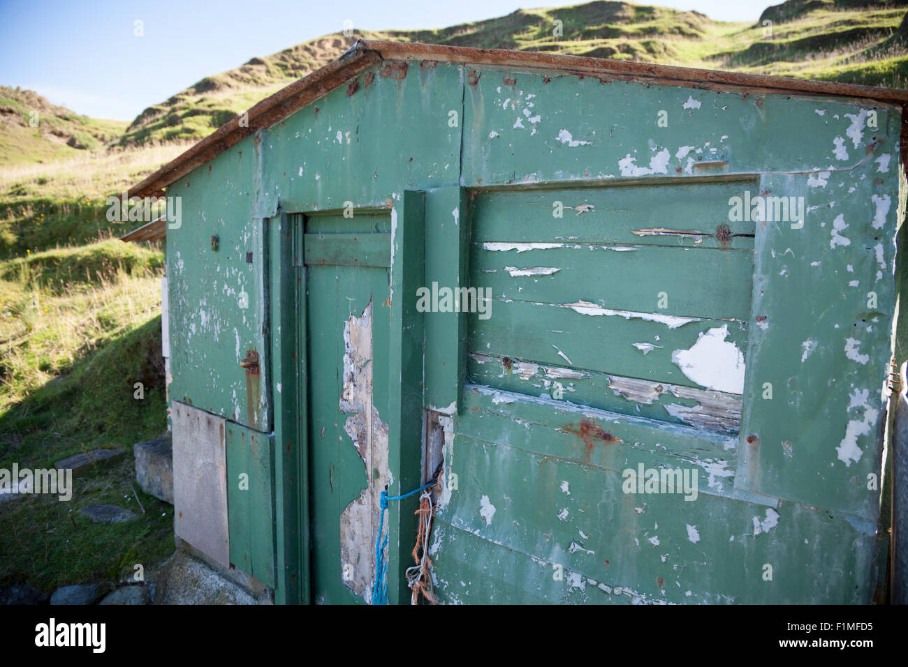 Abandoned fishing hut at Porth Ysgaden, Tudweiliog, Llyn Peninsula, North Wales with flaking green paint and rust Stock Photo