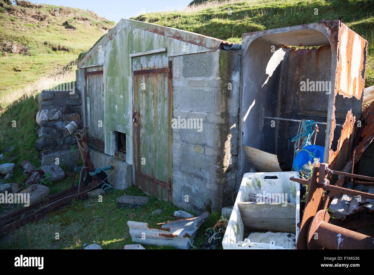 Abandoned fishing hut at Porth Ysgaden, Tudweiliog, Llyn Peninsula, North Wales with rope, crates, boxes, flaking paint and rust Stock Photo