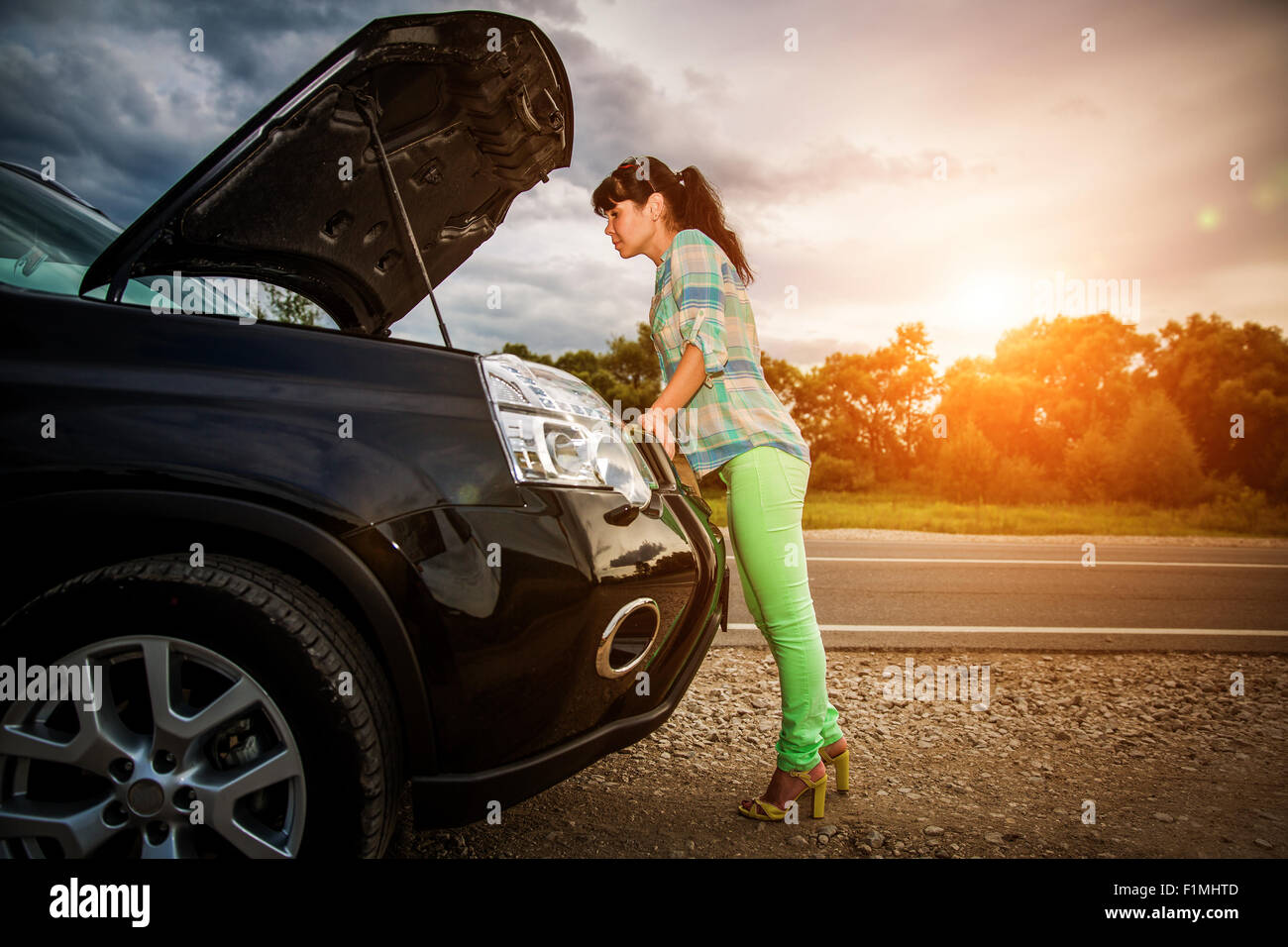 Woman on the road near the car. Damage to vehicle problems on the road. Stock Photo