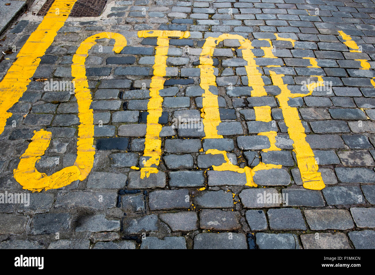 Yellow stop painted on cobbled stone road. Kelso, Scotland Stock Photo