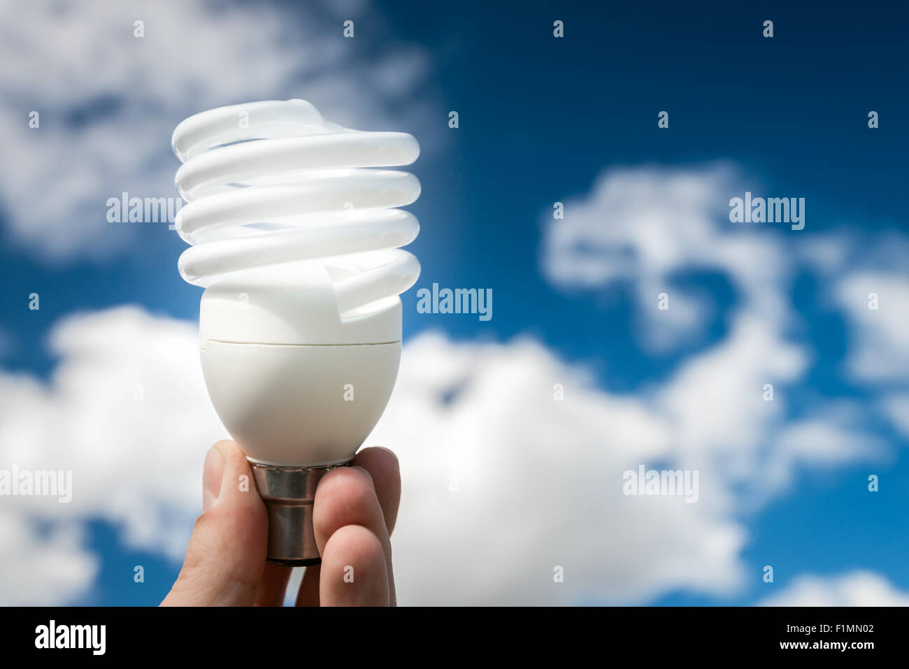 Energy efficient bulb in hand with blue sky in background Stock Photo ...