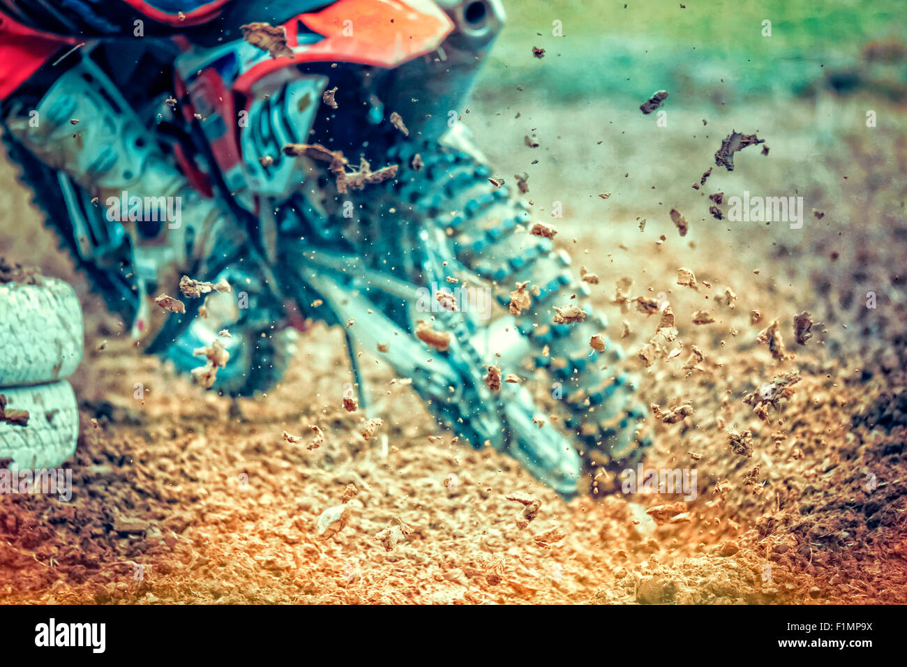 Rear view of drifting motocross bike. The rear wheel is digging deep in the mud and throws dirt in the air. Stock Photo