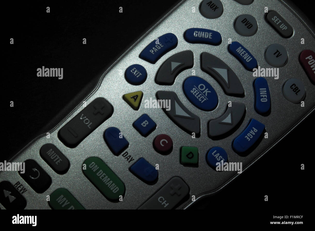 TV remote control device resting on a dark background in a spotlight. Stock Photo