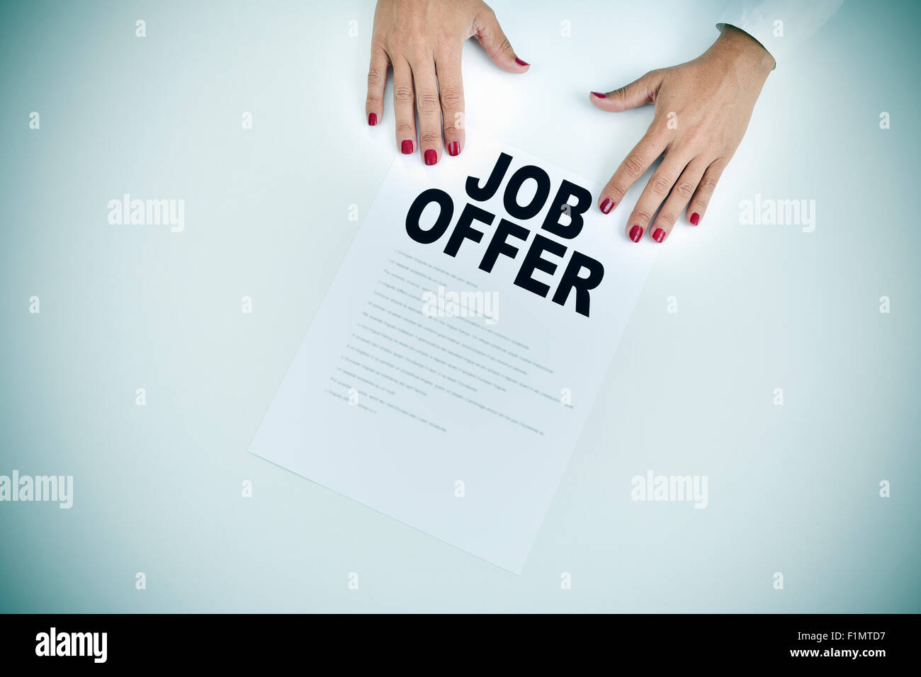 high-angle shot of the hands of a businesswoman with a document with the text job offer at an office desk Stock Photo