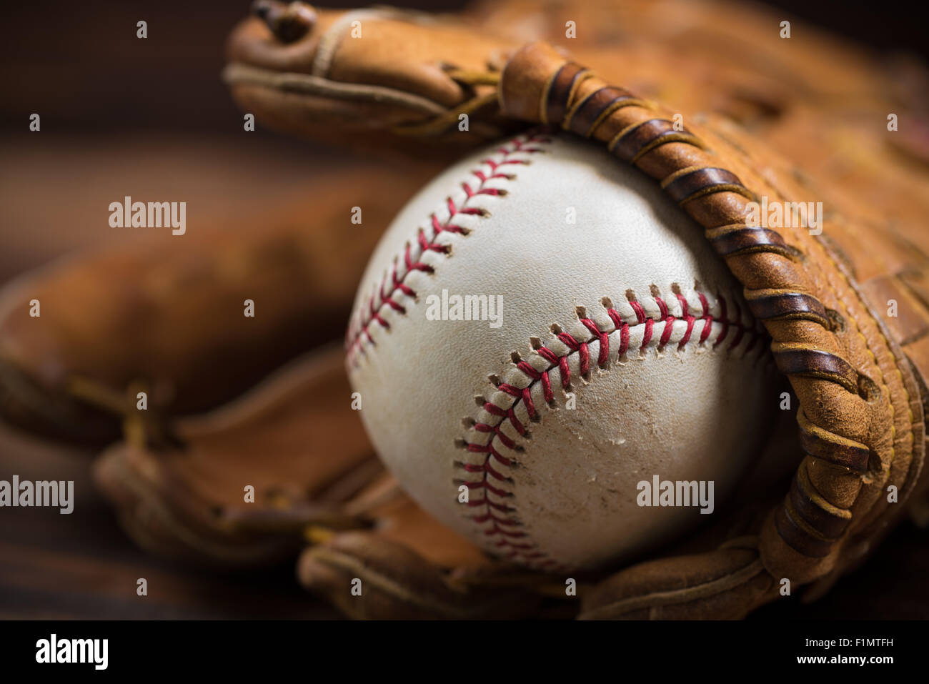 Brown leather baseball glove on a wooden bench Stock Photo