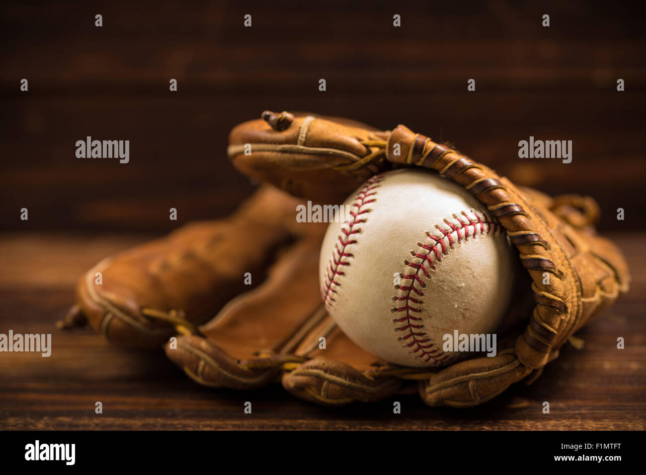Brown leather baseball glove on a wooden bench Stock Photo