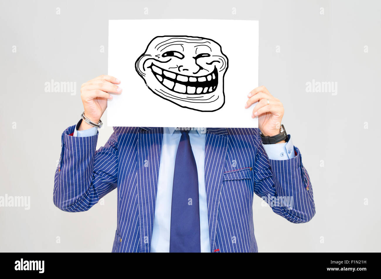 Business man hoding card with troll face isolated on grey background Stock Photo