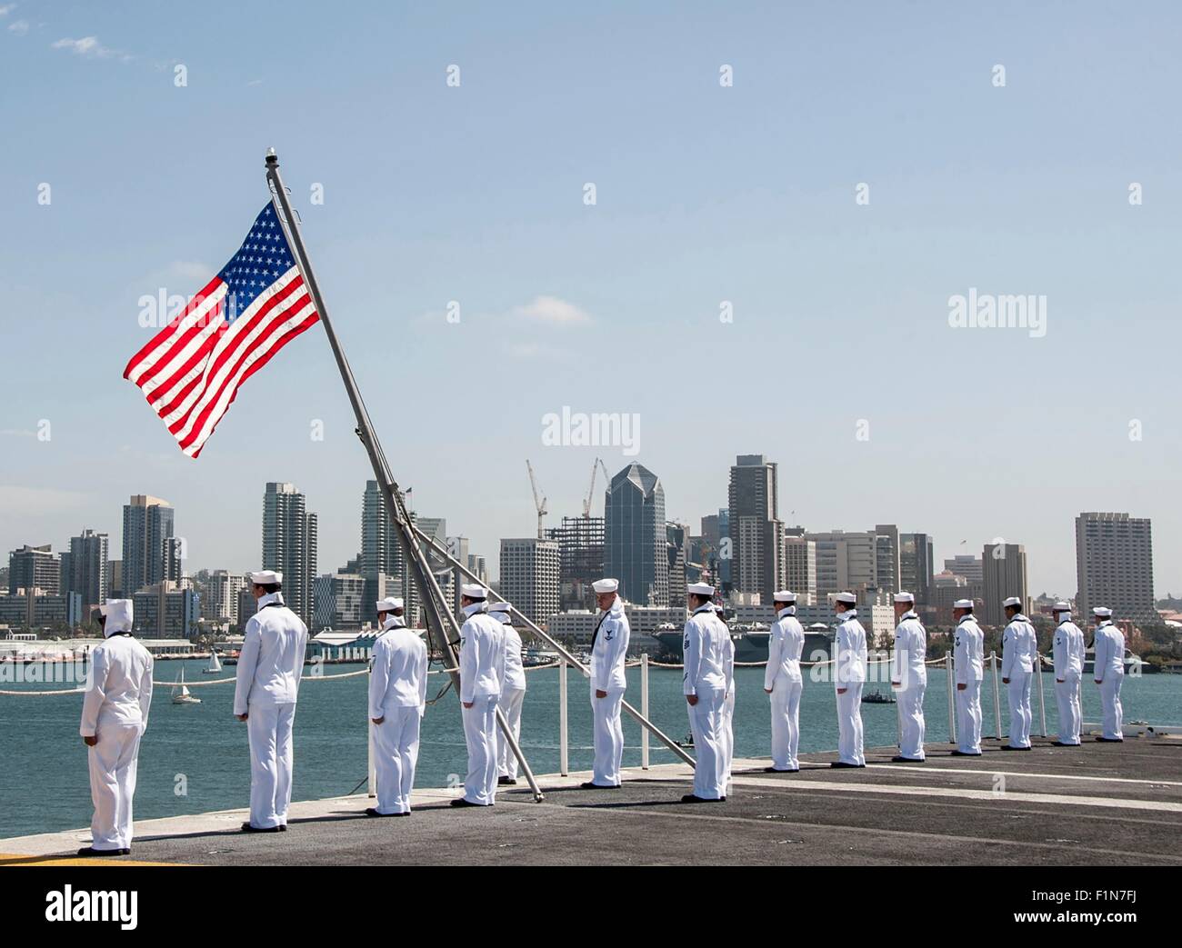 U.S. Navy Sailors man the rails on the flight deck of the Nimitz-class aircraft carrier USS Ronald Reagan as it departs for Japan August 31, 2015 in San Diego, California. Stock Photo