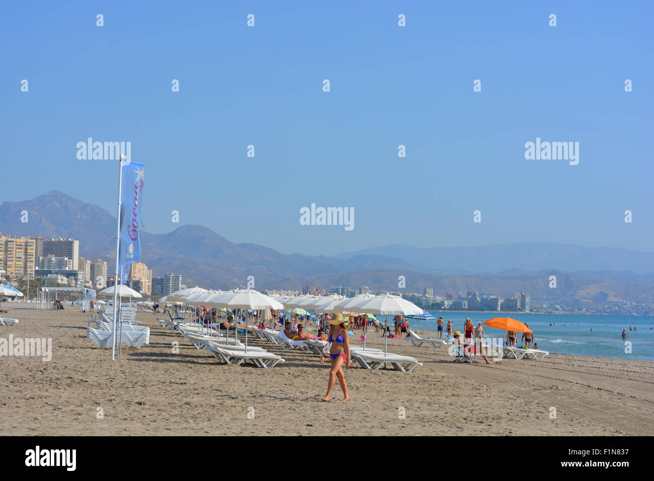 Early morning beach view with young girl leaving the beach at Campello, Alicante, Spain Stock Photo
