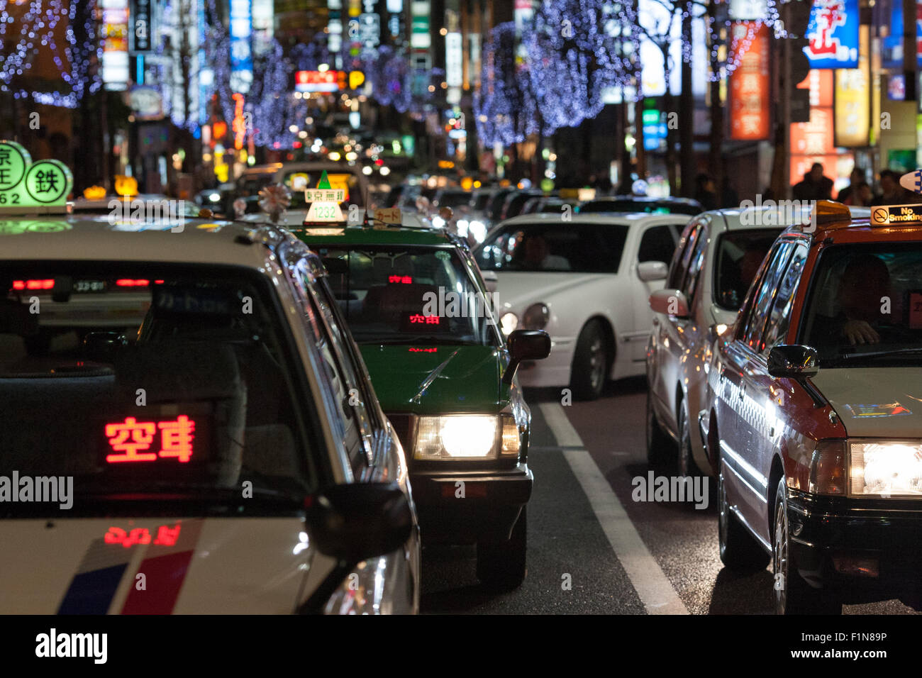 Japanese taxis in traffic with city lights in background Stock Photo