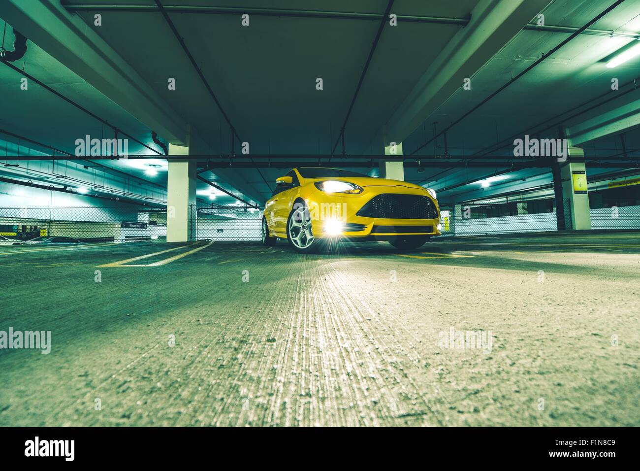 The Parking Space. Yellow Sports Car in Underground Parking at Night. Stock Photo