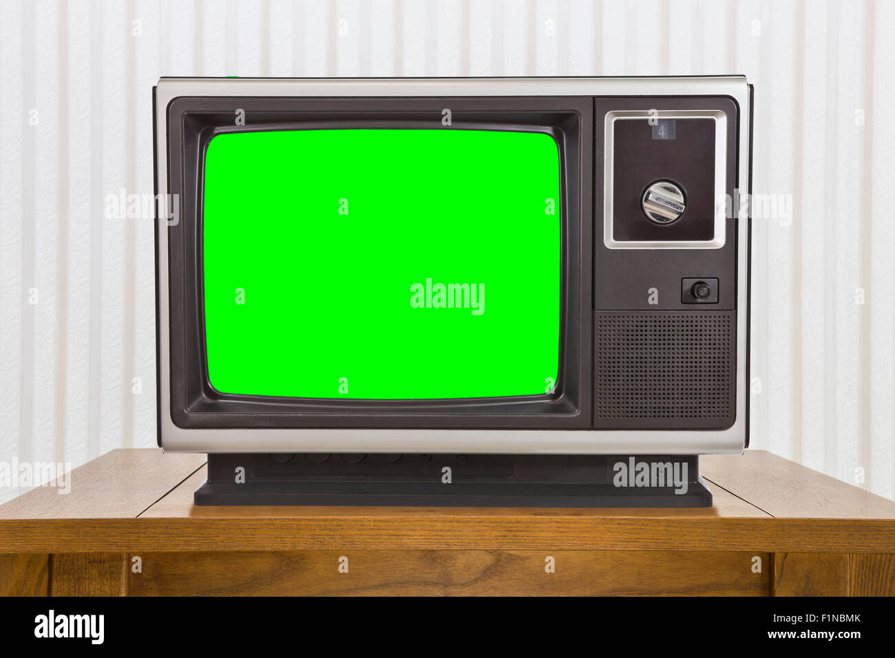 Old analogue portable television on table with green screen. Stock Photo