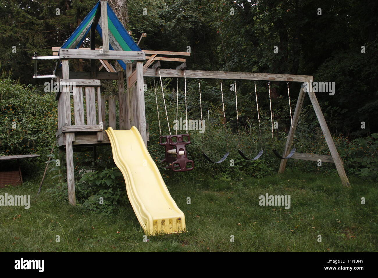 children's playscape at dusk with a yellow slide and swings Stock Photo