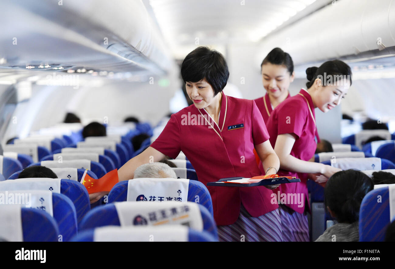(150905) -- BEIJING, Sept. 5, 2015 (Xinhua) -- Flight attendants send national flags to passengers on flight CZ6366 from Beijing, capital of China, to Haikou, capital of south China's Hainan Province, Sept. 5, 2015. China Southern Airlines started an event called 'In Commemoration of Beijing V-day parade' on a Beijing-Haikou flight Saturday, showing the parade photos for passengers. China on Thursday held commemoration activities, including a grand military parade, to mark the 70th anniversary of the victory of the Chinese People's War of Resistance against Japanese Aggression and the World An Stock Photo