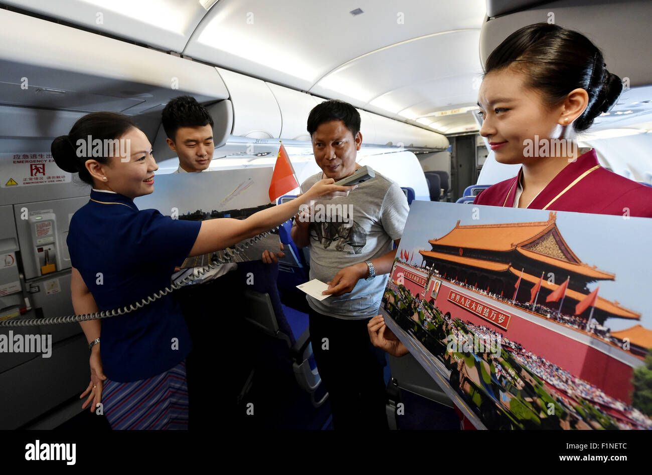 (150905) -- BEIJING, Sept. 5, 2015 (Xinhua) -- A flight attendant (R) shows photos of Beijing V-day parade on flight CZ6366 from Beijing, capital of China, to Haikou, capital of south China's Hainan Province, Sept. 5, 2015. China Southern Airlines started an event called 'In Commemoration of Beijing V-day parade' on a Beijing-Haikou flight Saturday, showing the parade photos for passengers. China on Thursday held commemoration activities, including a grand military parade, to mark the 70th anniversary of the victory of the Chinese People's War of Resistance against Japanese Aggression and the Stock Photo