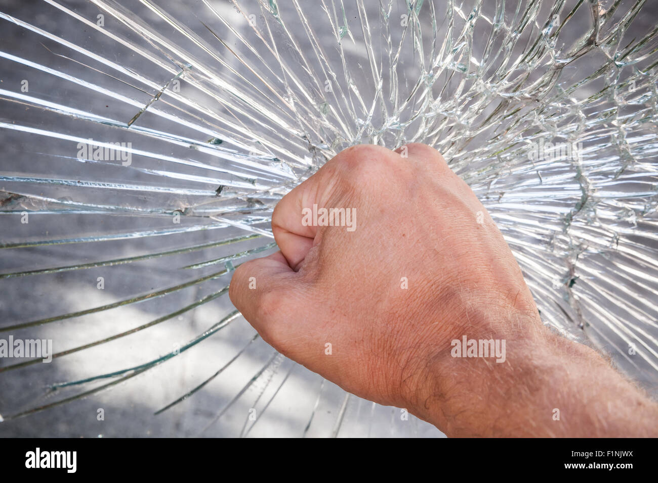 Strong male fist and broken window glass Stock Photo