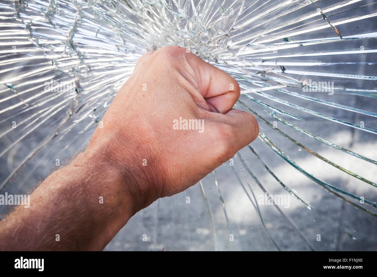 Powerful male fist with broken window glass Stock Photo
