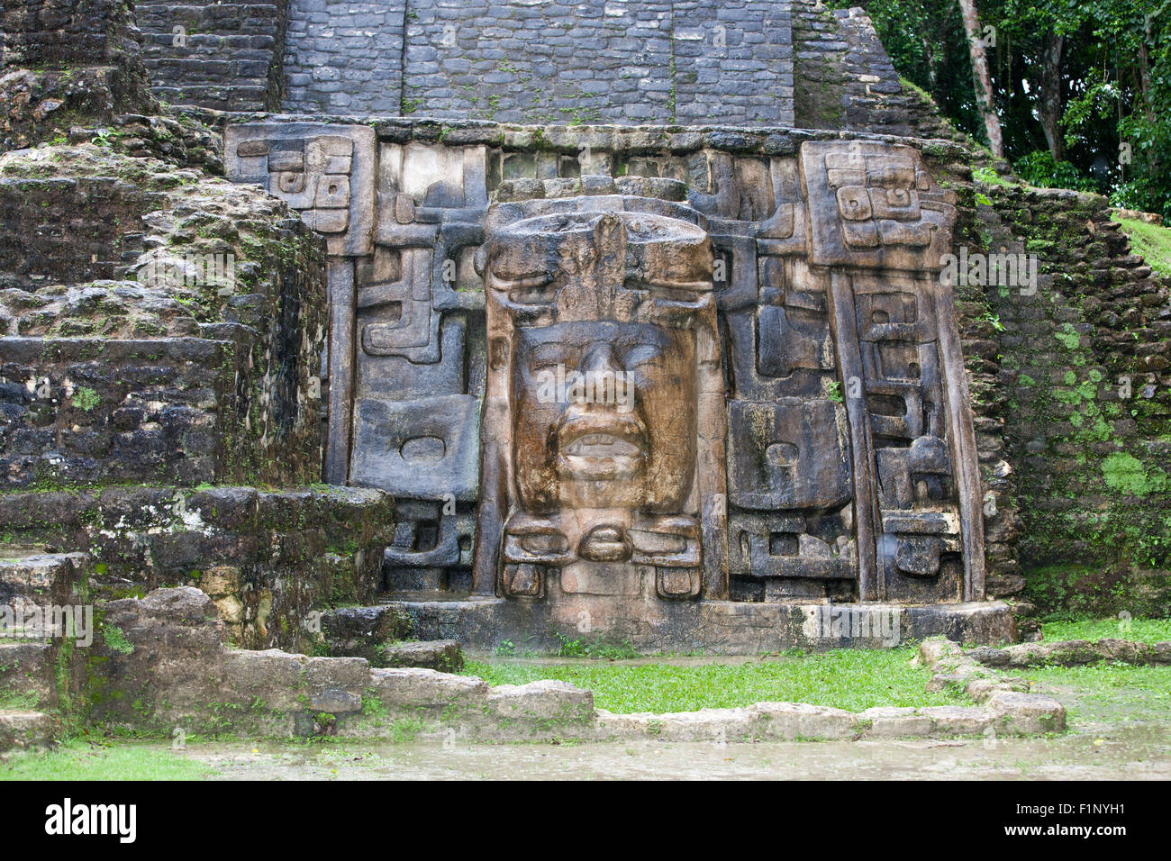 An Olmec style face adorns the side of the Mask Temple wall at the Mayan site of Lamanai in Belize. Stock Photo