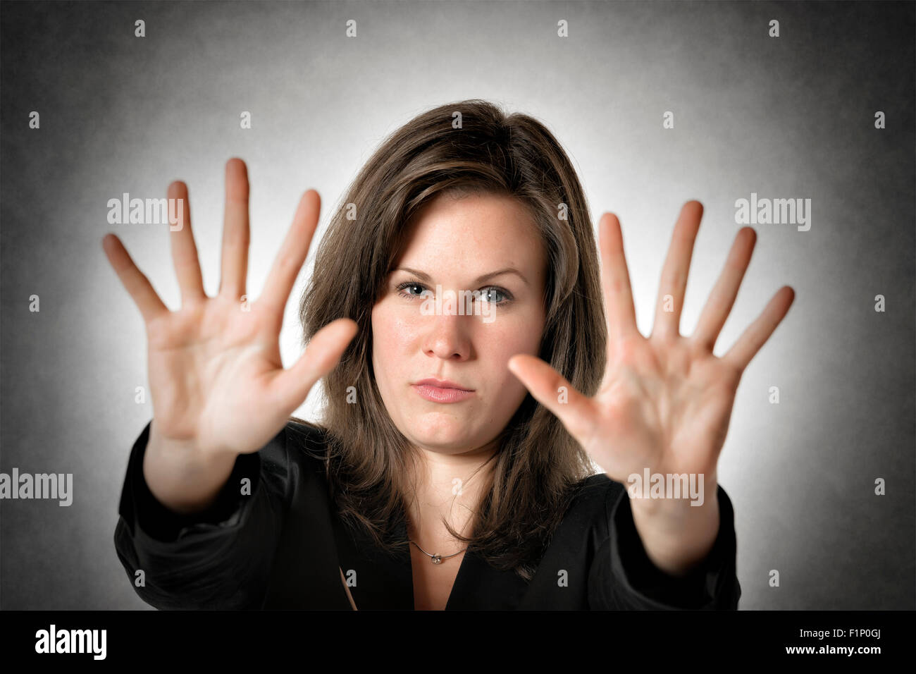 Business woman in black suit holds both hand up to stop someone or something Stock Photo