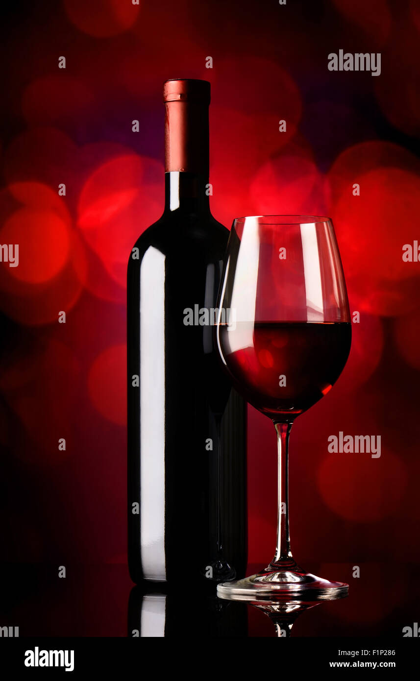 Bottle and glass with red wine on red background Stock Photo