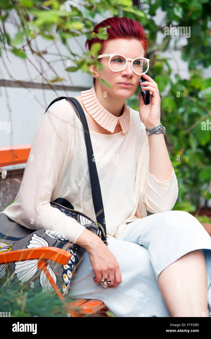 red-haired woman sitting on a bench and talking on the phone Stock ...