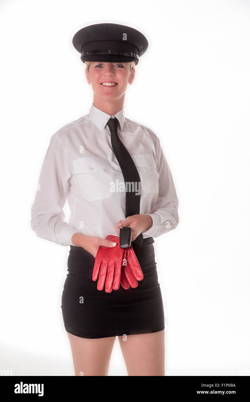 A uniformed chauffeuse standing in a mini skirt wearing a black hat and holding driving gloves. A professional female chauffeur Stock Photo