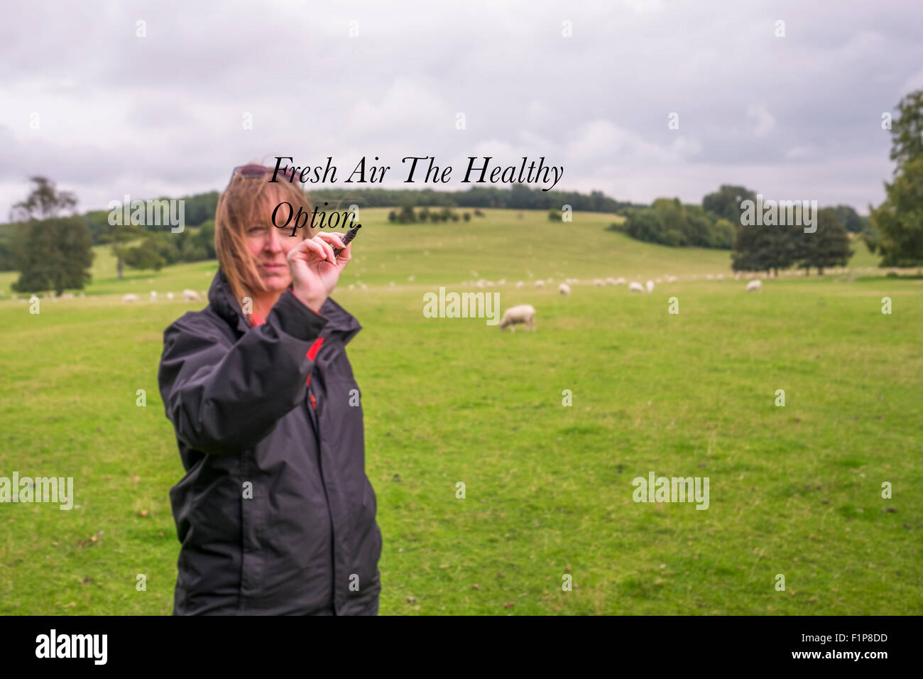 A middle aged woman standing outside in the fresh air of the southdowns national park writing on the words on a invisible screen Stock Photo