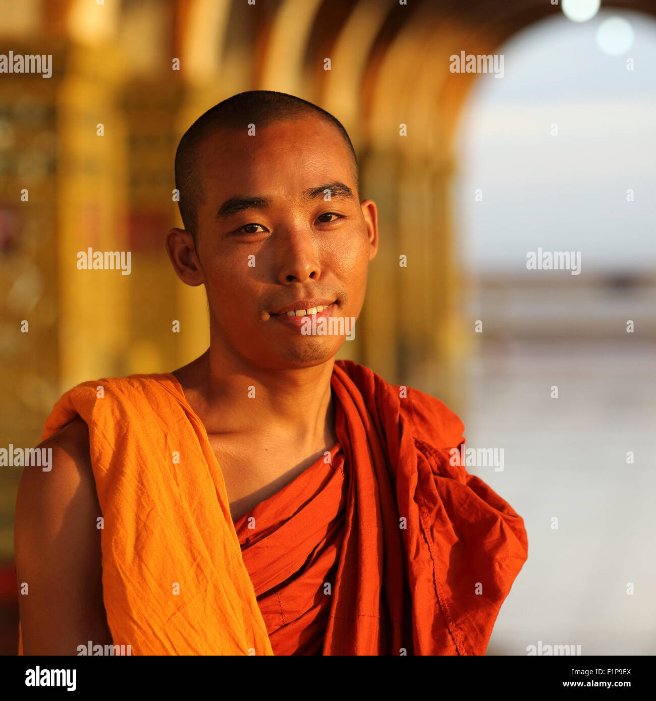 Buddhist monk at the Sutaungpyei Pagoda in Mandalay, Myanmar. The monk stands under one of the temple's arches. Stock Photo