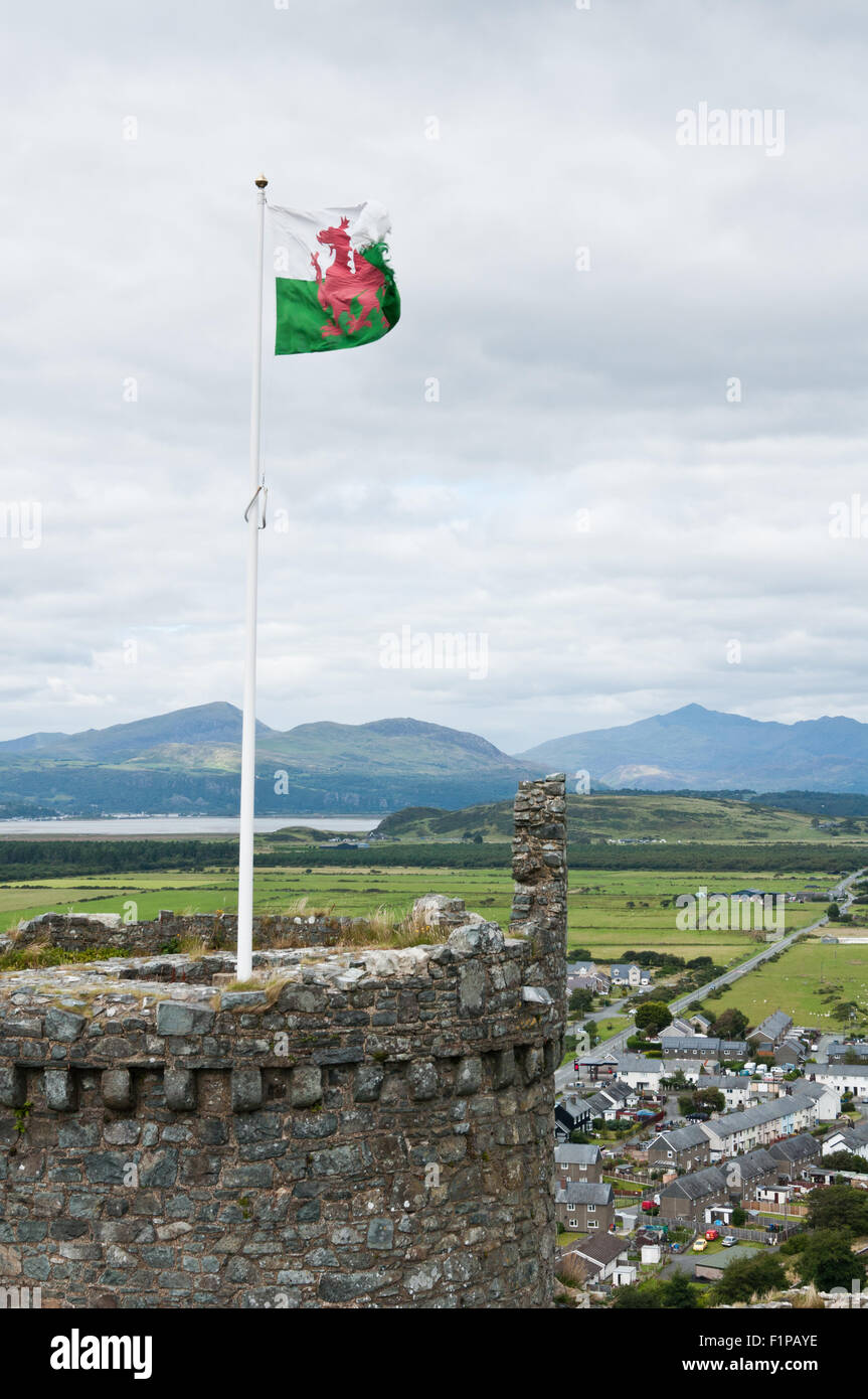 The Welsh flag flies from a tower at Harlech castle, dominating the castle approaches, with the Snowdonia mountains behind Stock Photo