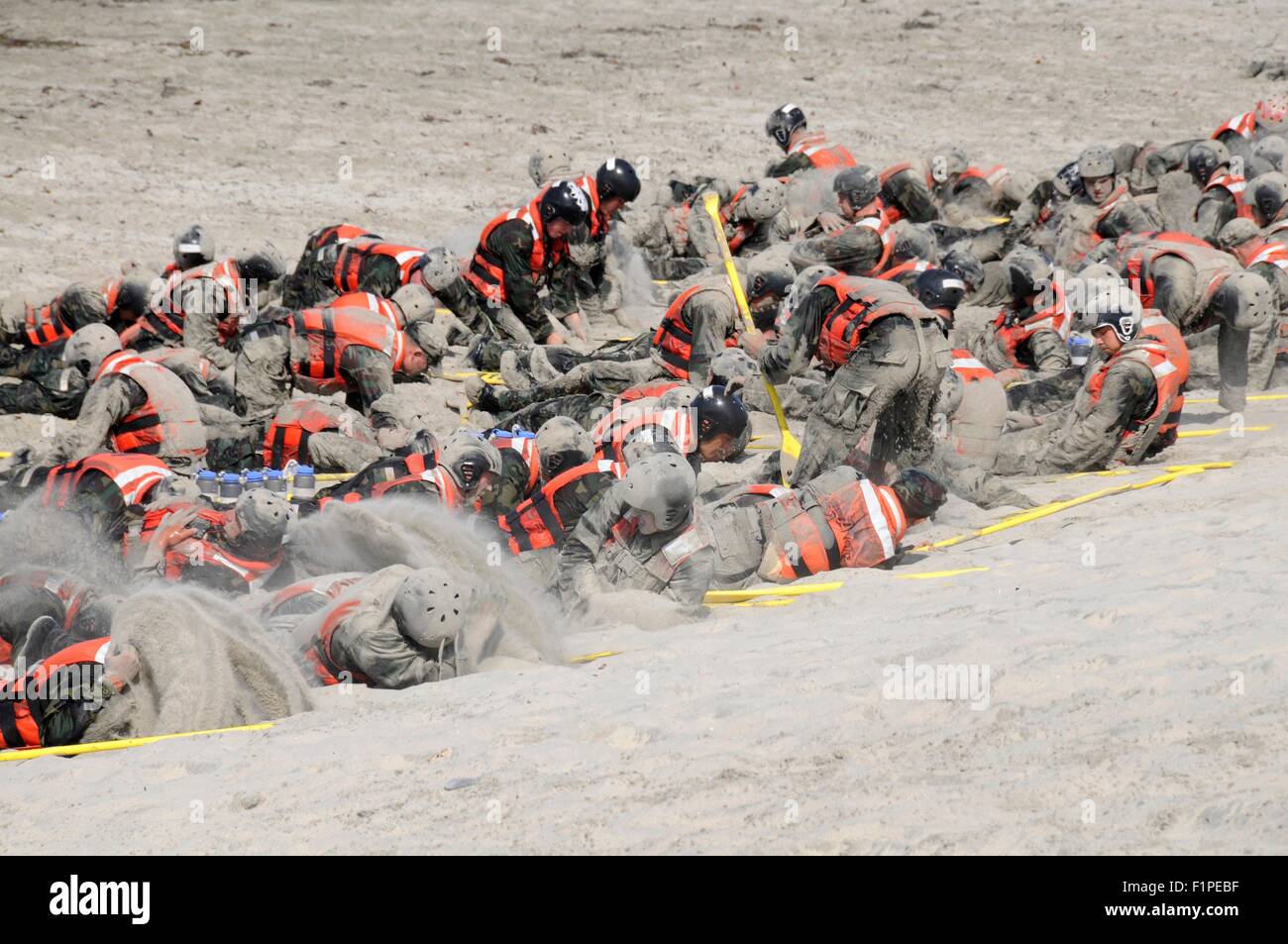 US Navy SEAL candidates cover themselves in sand during surf passage on Naval Amphibious Base Coronado September 2, 2015 in San Deigo, California. Stock Photo