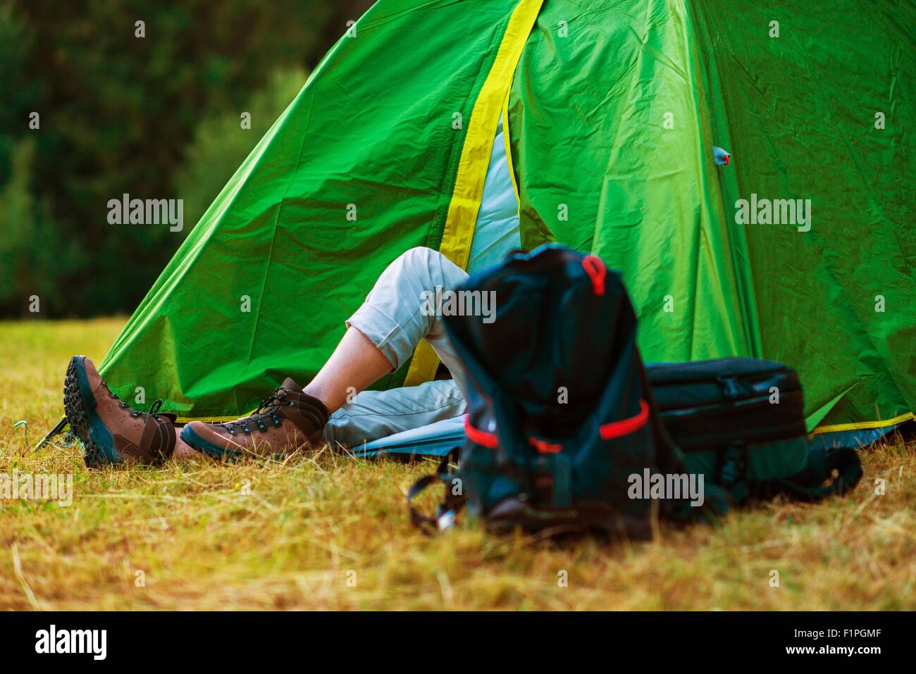 Resting Hiker in His Medium Size Tent. Wild Campsite. Hiking and Tent Camping Theme. Stock Photo