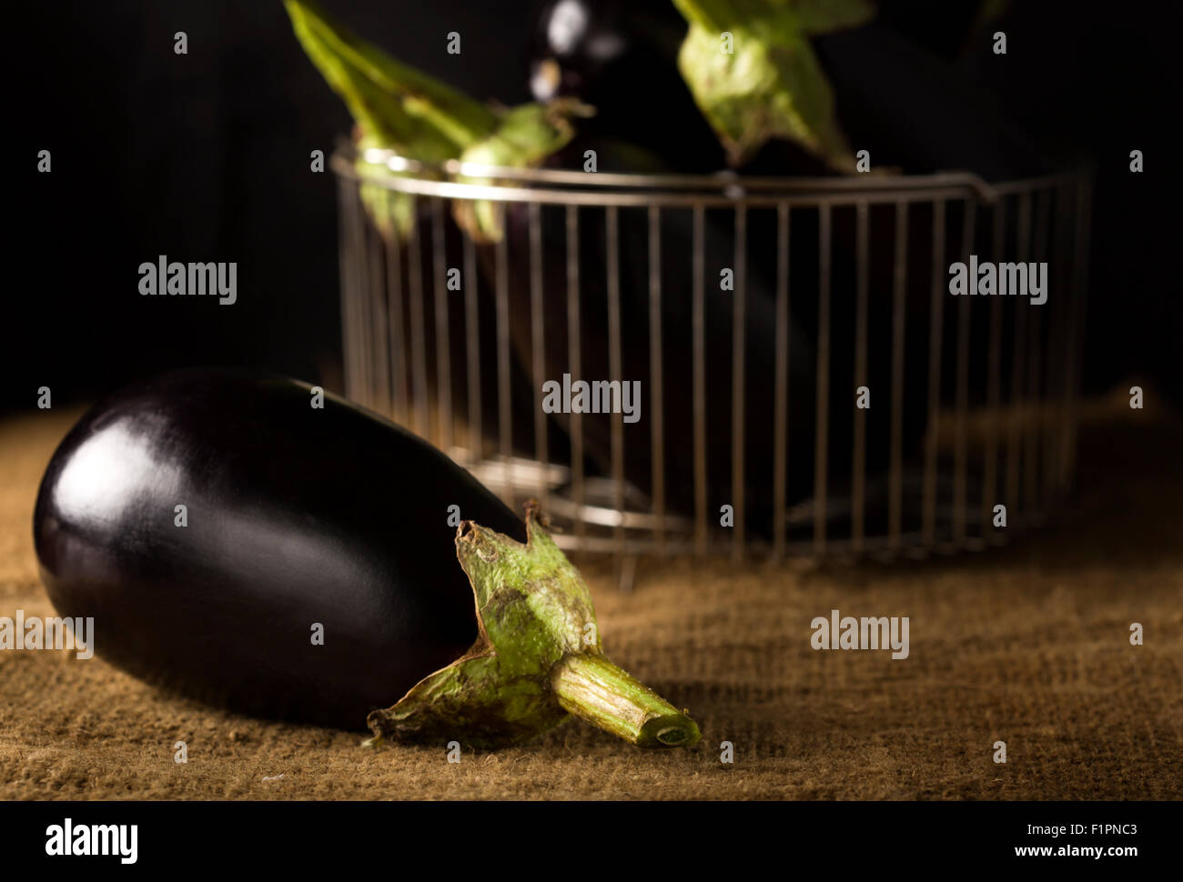 Eggplant on a old canvas bag and others in metallic strainer Stock Photo