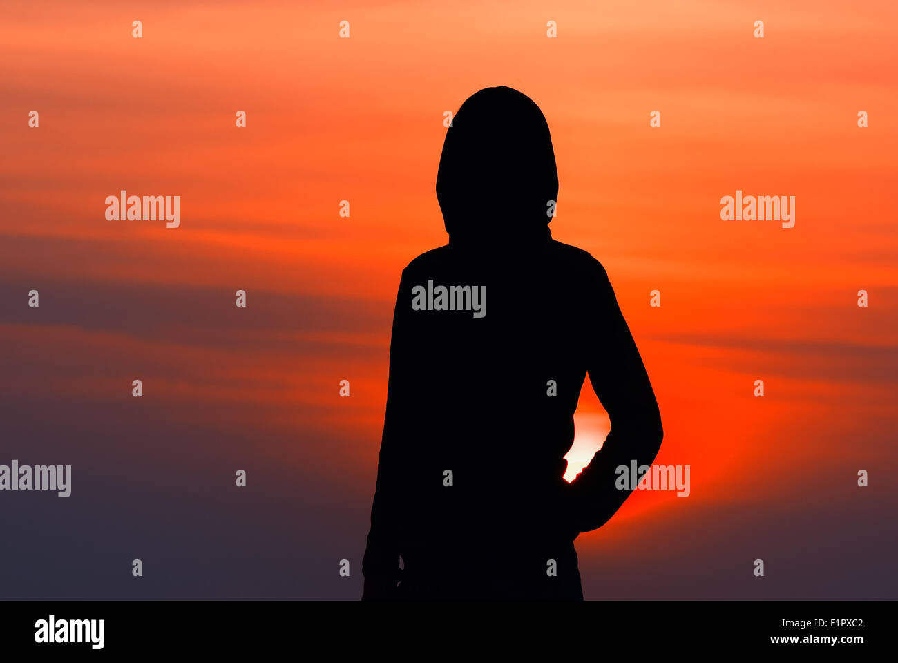silhouette of the girl in sportswear with a hood at sunset Stock Photo