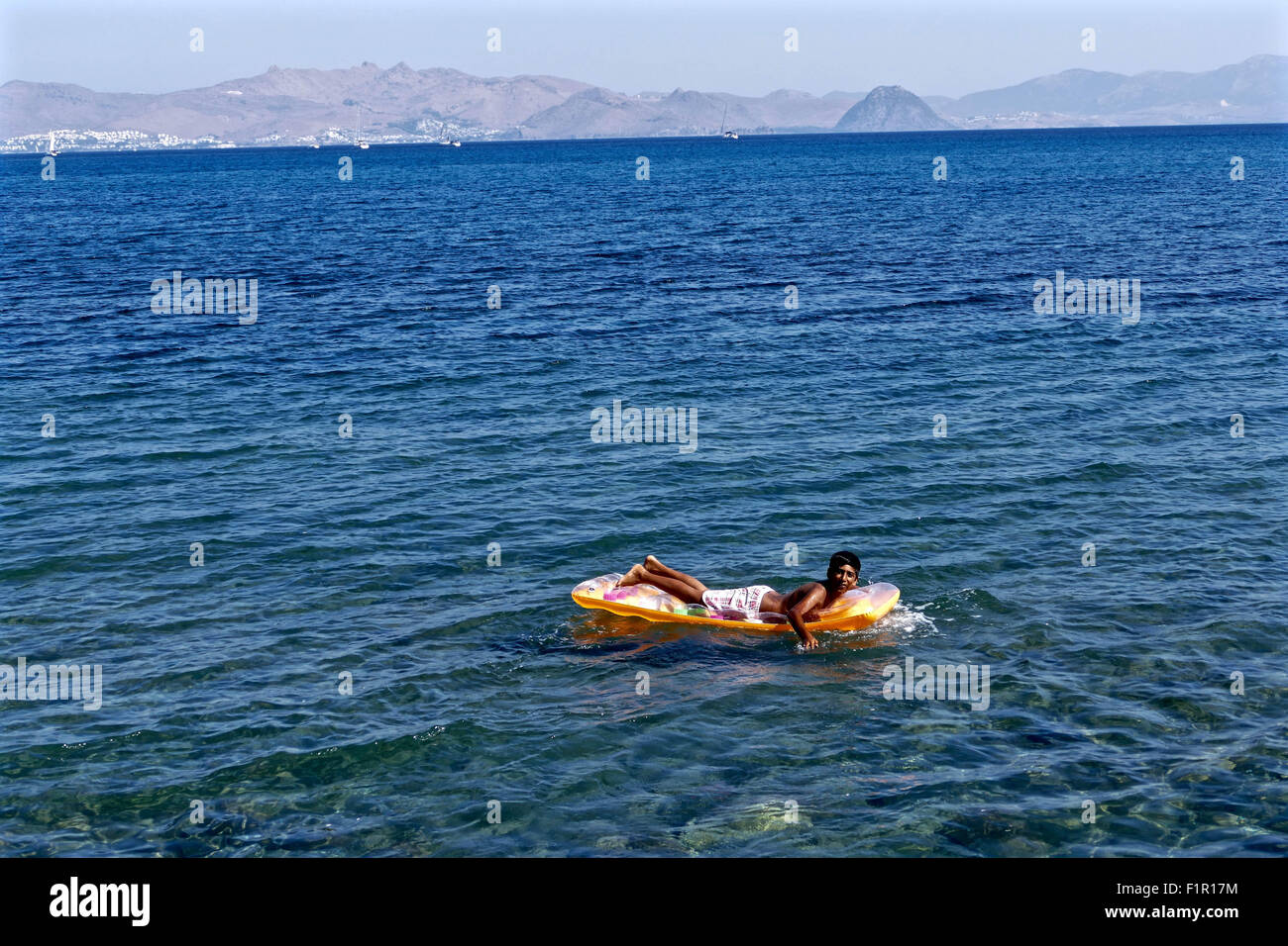 From the marina area where hundreds of refugees are camping out, you can see Turkey, Bodrum where the refugees leave at night to reach Kos, Greece. The distance is approximately 13 miles and looks calm by day, but at night it becomes treacherous. The beaches are littered with soaked belongings that were carried by the refugees and left along the marina beach in Kos. Many refugees recycle the items. Many have beach floats that they use play around in the same Sea they made the treacherous journey a few days before. 4th Mar, 2014. © Gail Orenstein/ZUMA Wire/Alamy Live News Stock Photo