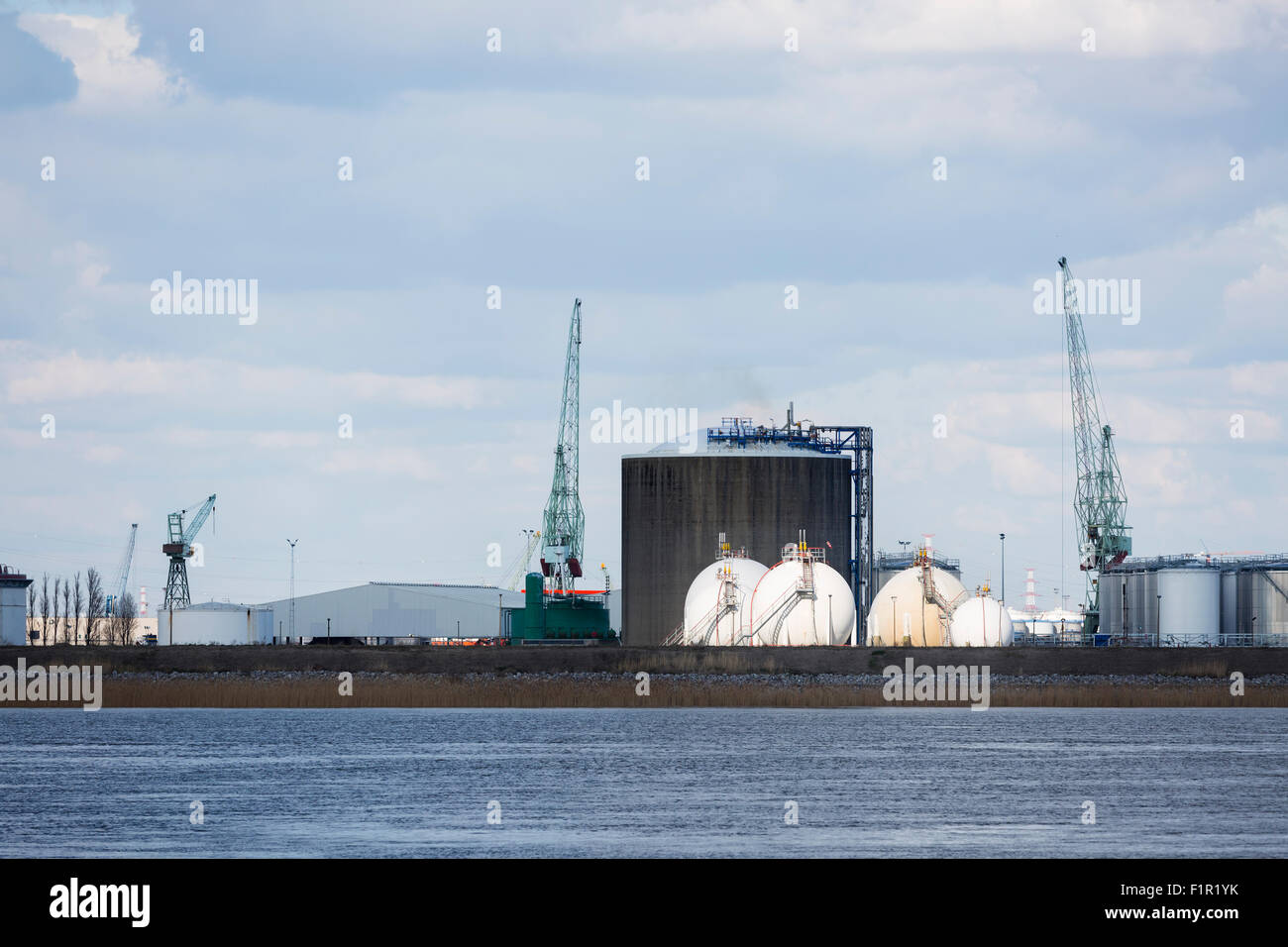Oil and gas storage tanks in the port of Antwerp, Belgium with sunlight exclusively on the gas