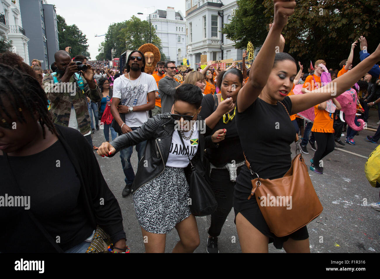 Dancing behind one of the parade sound systems. Notting Hill Carnival in West London. A celebration of West Indian / Caribbean culture and Europe's largest street party, festival and parade. Revellers come in their hundreds of thousands to have fun, dance, drink and let go in the brilliant atmosphere. It is led by members of the West Indian / Caribbrean community, particularly the Trinidadian and Tobagonian British population, many of whom have lived in the area since the 1950s. The carnival has attracted up to 2 million people in the past and centres around a parade of floats, dancers and sou Stock Photo