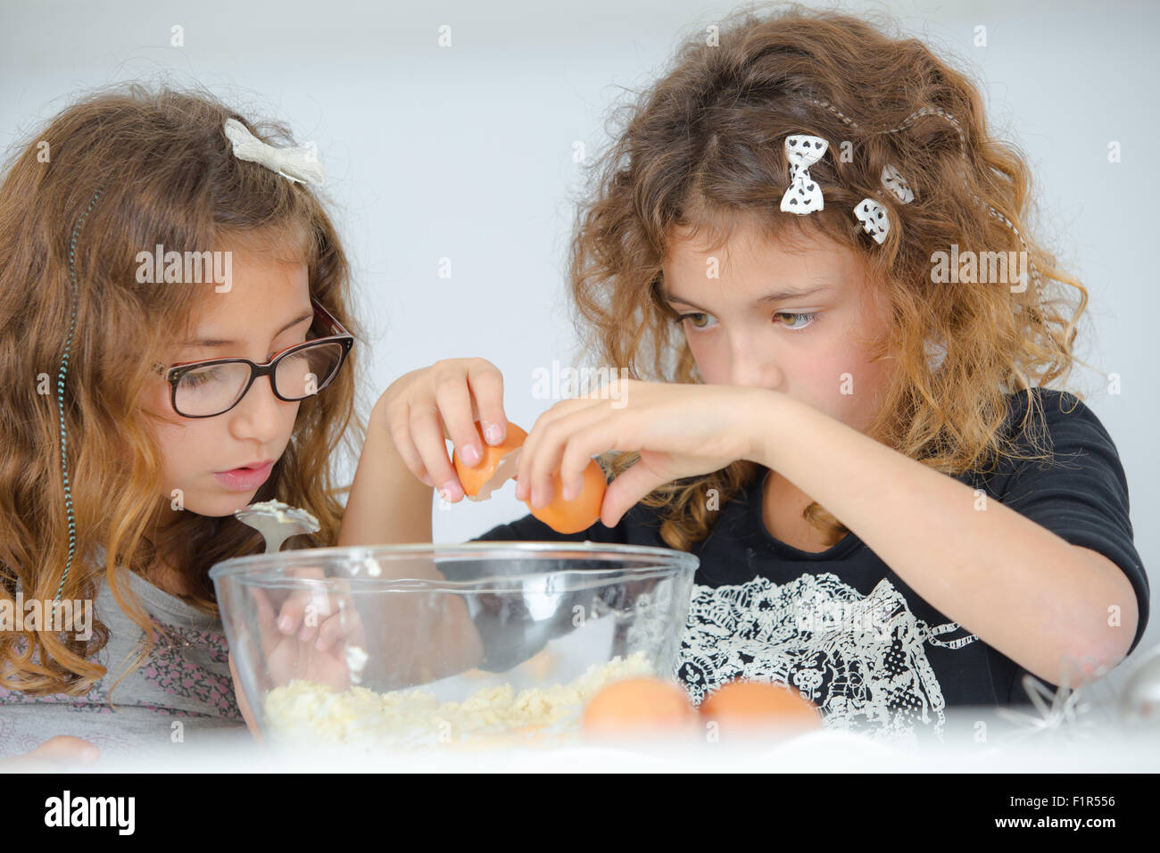 School girls breaking eggs into a bowl Stock Photo